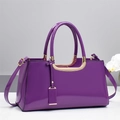 Detail of glossy purple patent leather handbag with gold-tone hardware and orchid decor - Purple