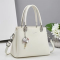 Detalle de bolso blanco en cuero con textura de lichi, herrajes plateados y dije de concha - Blanco Roto
