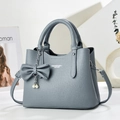 Detalle de bolso en cuero con grano lichi, lazo decorativo y colgantes de perlas - Azul