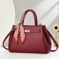Close-up of wine red lychee leather handbag with silver lock and decorative silk scarf - Wine Red