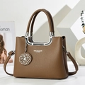 Detalle de bolso de cuero marrón con colgante de flor de metal y logotipo de moda - Caqui Oscuro