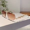 Detail der Y2K-Sonnenbrille mit Nietbügeln und Kristallbesatz auf goldenem Metallrahmen - Verlaufend Braun Goldener Bügel