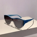 Dettaglio degli occhiali da sole oversize blu acceso su un supporto geometrico bianco - Montatura blu trasparente lenti grigie