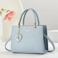 Bolso de mano azul claro en cuero con colgante de corazón y correa sobre fondo blanco - Azul