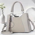 Detailed view of grey lychee leather handbag with woven tassel and silver hardware - Gray