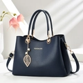 Dettaglio della borsa blu navy in pelle a grana con ciondolo a foglia d'oro e perla - Blu