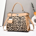 Close-up of leopard print handbag with silver twist lock and mini charm accessory - Khaki