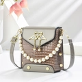 Close-up of a mini handbag featuring crocodile texture and a golden swan clasp with pearls - Gray
