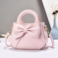Pink fashion handbag with large bow decoration and gold hardware on elegant background - Pink