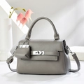 Détail d'un sac à main gris en cuir grainé avec fermoir rotatif argenté et mini breloque - Gris