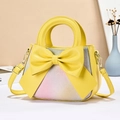 Elegant yellow handbag with large bow and floral gradient pattern on modern background - Yellow
