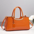 Detail of orange faux-crocodile leather handbag with gold metal lock and dual handles - Orange