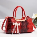 Elegant red crocodile embossed handbag with gold handles and pearl bow charm - Red