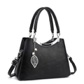 Elegante bolso de mano en cuero negro con colgante de hoja y detalle de perla - Negro