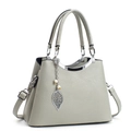 Sac à main élégant en cuir gris avec pendentif feuille et perle sur fond blanc pur - Gris