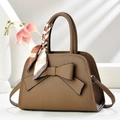 Detail of a brown lychee pattern handbag with a large bow and silk scarf decoration - Brown