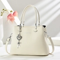 Détail du sac cabas beige en cuir grainé avec pendentif en métal et logo mode - Blanc Cassé