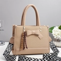 Close-up of straw texture and leather bow detail on a beige crossbody tote bag - Khaki