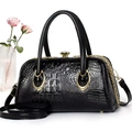 Close-up of black crocodile texture handbag with gold chain detail and metal lock - Black