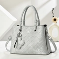 Detail of metallic grey woven handbag with brand lettering and clover charm - Gray