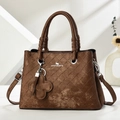 Close-up of brown textured leather handbag featuring diamond quilt pattern and logo detail - Coffee
