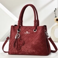 Macro detail of wine red woven lattice texture and metallic logo on women's bag - Wine Red