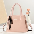 Close-up of pink woven textured crossbody bag with chocolate pendant and branded text - Pink