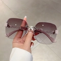 Close-up of rimless gradient sunglasses with metal chain detail and glitter accents - Double Grey Lenses