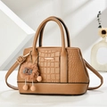 Brown crocodile embossed tote bag with teddy charm on a minimalist studio background - Brown