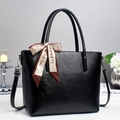 Elegant black leather tote bag with decorative silk scarf and adjustable strap on a gray background - Black