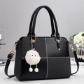 Black leather crossbody bag with woven panels, white stitching, and a plush monster charm - Black