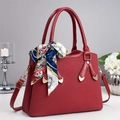 Détail du sac rouge en cuir grainé avec une écharpe en soie florale et des détails dorés - Bordeaux