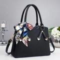 Detalle de bolso negro de piel con textura, pañuelo de seda decorativo y piezas metálicas - Negro