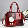 Deep red patent leather tote bag with crocodile pattern side panels and plush charm - Red