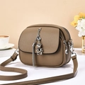 Brown leather crossbody bag with silver bear charm and tassel on a minimalist background - Khaki