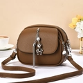 Detail of brown litchi grain leather bag with silver bear pendant and long tassels - Brown