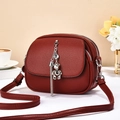 Detail of burgundy leather shoulder bag with silver bear pendant and zipped sections - Red