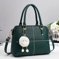 Detail of dark green handbag featuring lychee and crocodile textures with plush charm - Dark Green