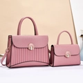 Close-up of pink leather handbag set with litchi texture and metal twist lock - Pink
