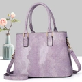 Detail view of lavender textured tote bag with golden hardware and floral decor - Purple