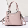Detailed macro view of pink pebbled leather handbag with silver logo and star charm detail - Pink