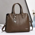 Detail of dark brown pebble leather handbag featuring pearl charm and adjustable strap - Brown
