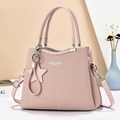 Pink textured shoulder bag with round handles and detachable strap in a soft setting - Pink