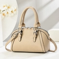 Detalle de bolso beige de piel granulada con herrajes plateados y asas redondeadas - Caqui