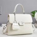Detail der weißen Handtasche aus Litschi-Leder mit G-Schnalle und Mini-Anhänger - Cremeweiß