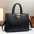 Black large capacity tote bag with gold B buckle and adjustable strap in a cozy setting - Black