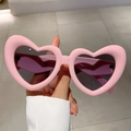 Detailansicht der glänzend rosa Herz-Sonnenbrille mit dunklen Gläsern und glatter Form - Rosa Rahmen Graue Linse