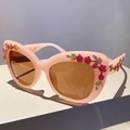 Vintage cat eye sunglasses with pink floral frame and amber lenses on a podium - Pink Frame Tea