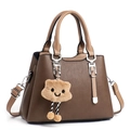 Dettaglio borsa in pelle marrone con tracolla a contrasto e ciondolo peluche a stella - caffè