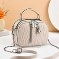 Quilted beige underarm bag with silver chain strap and bear charm in a chic setting - Off-white